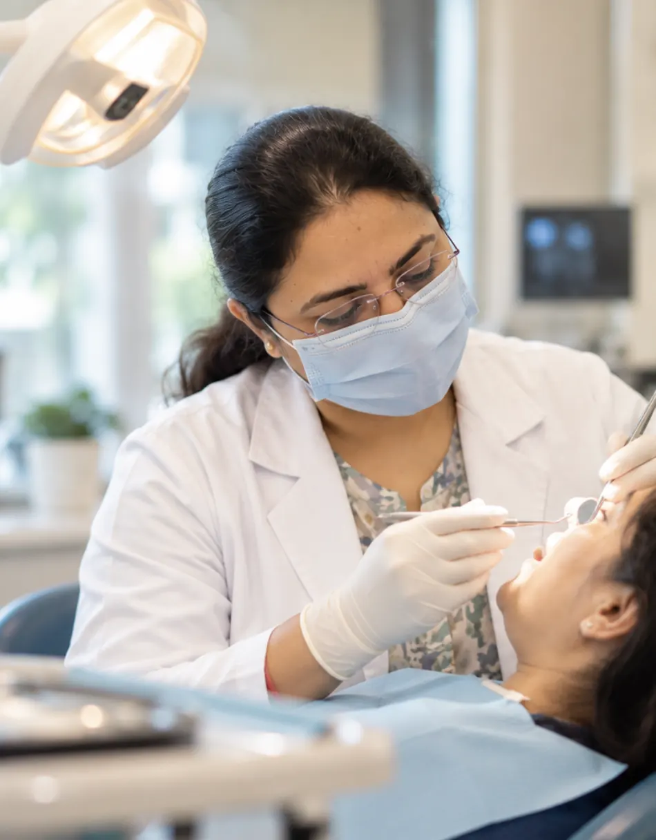 Dr. Deepshikha Rathore examining a patient's teeth with a mirror and probe